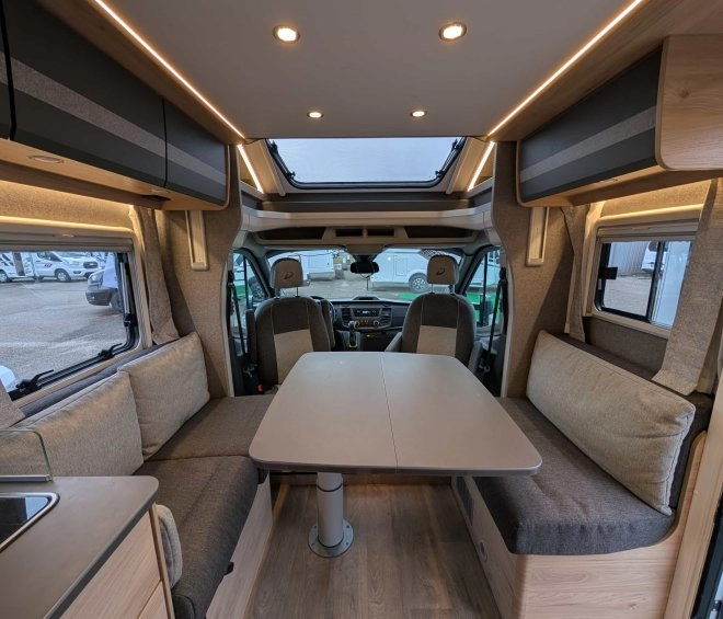 Intérieur d'un camping-car moderne avec table et banquettes grises