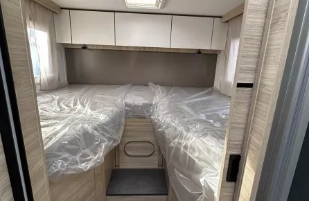 Intérieur d'une caravane avec lits jumeaux et rangements en bois clair.