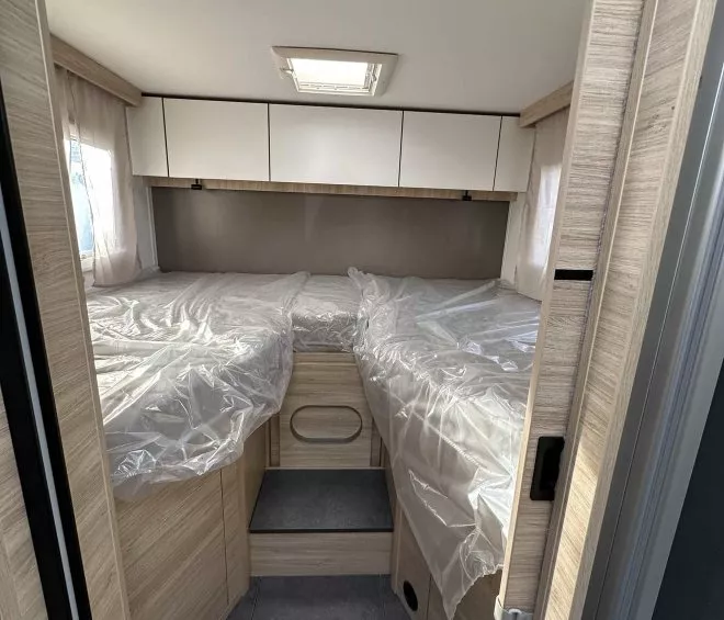 Intérieur d'une caravane avec lits jumeaux et rangements en bois clair.