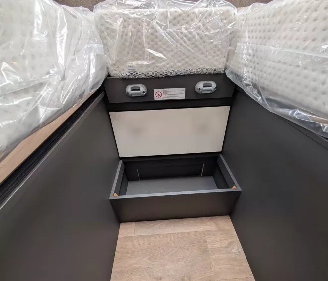 Coffre de rangement sous un lit avec matelas emballés en plastique