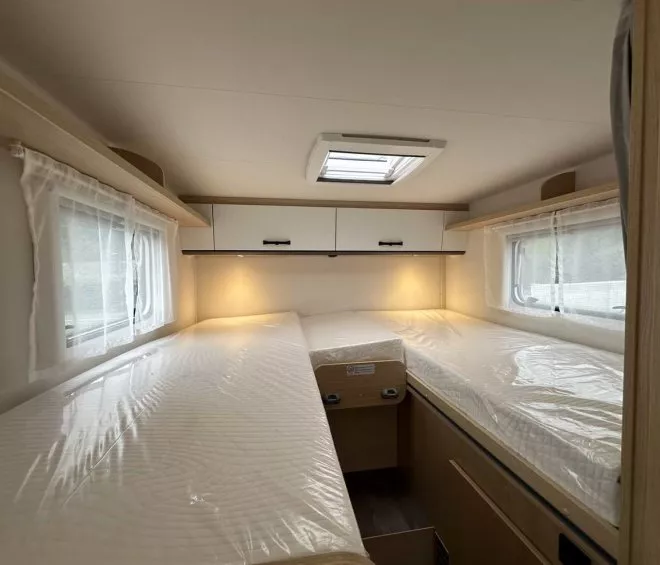 Intérieur d'une caravane avec deux lits simples et rangements.
