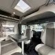 Intérieur d'un camping-car moderne avec sièges et table, vue sur l'extérieur.