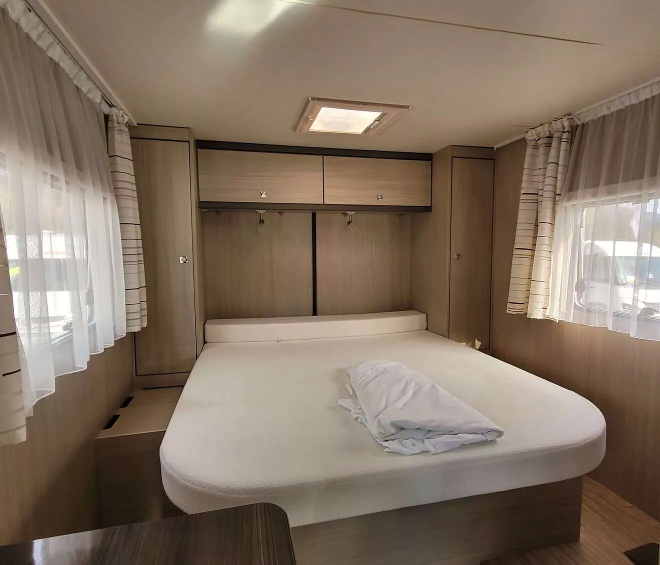 Intérieur d'une caravane avec lit double et rangements en bois clair