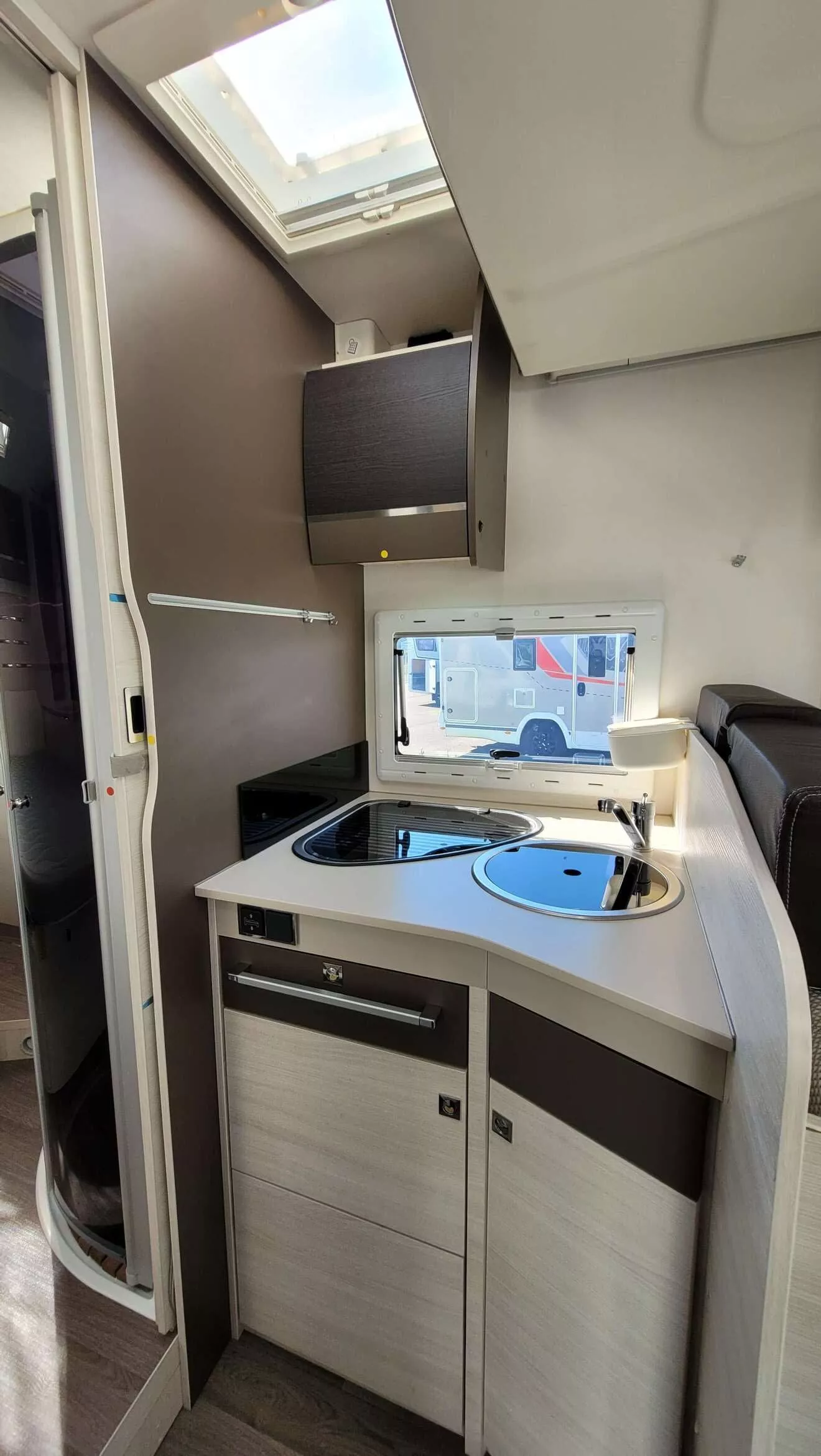 Cuisine compacte de camping-car avec évier, plaque de cuisson et fenêtre.