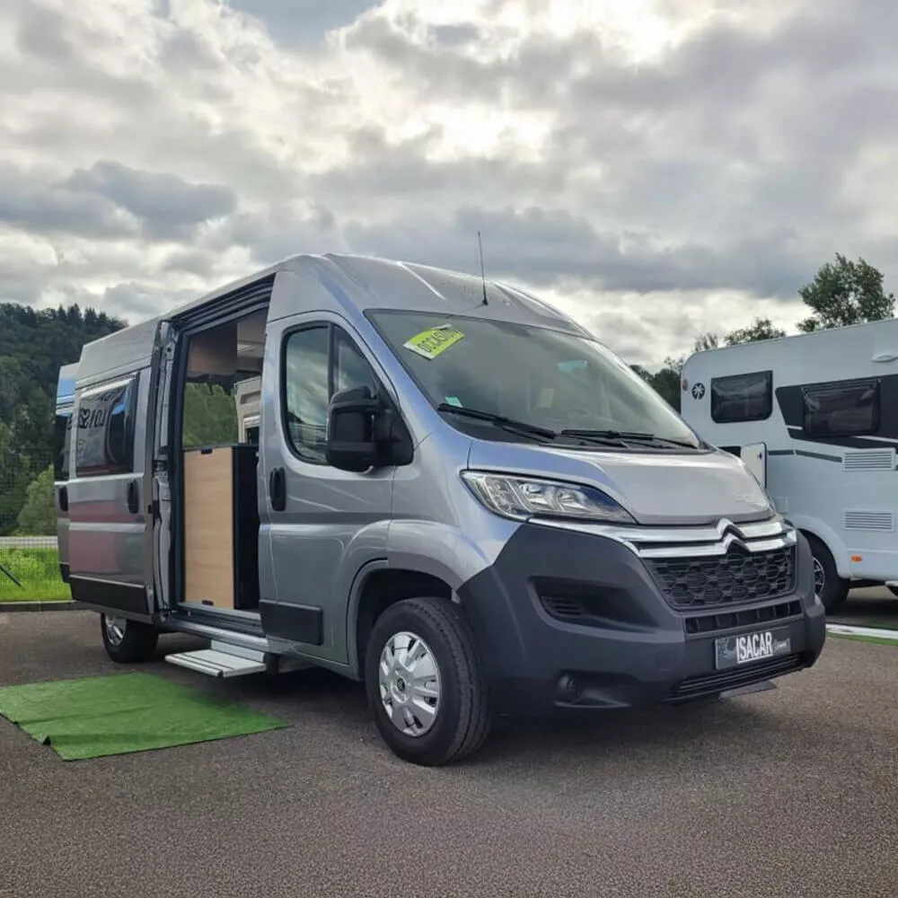 Fourgon aménagé Citroën gris stationné sur un parking, porte latérale ouverte