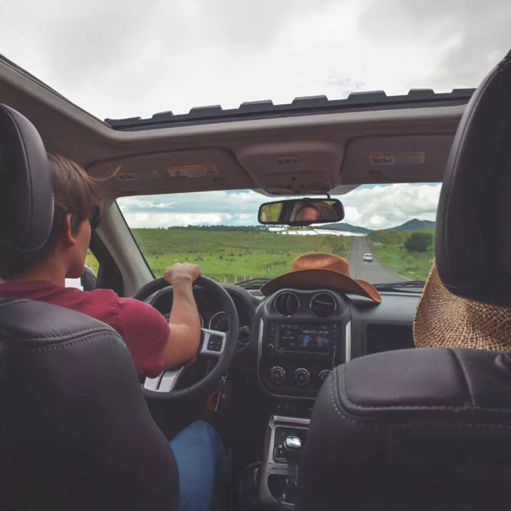 Conducteur sur route de campagne avec vue dégagée par le toit ouvrant