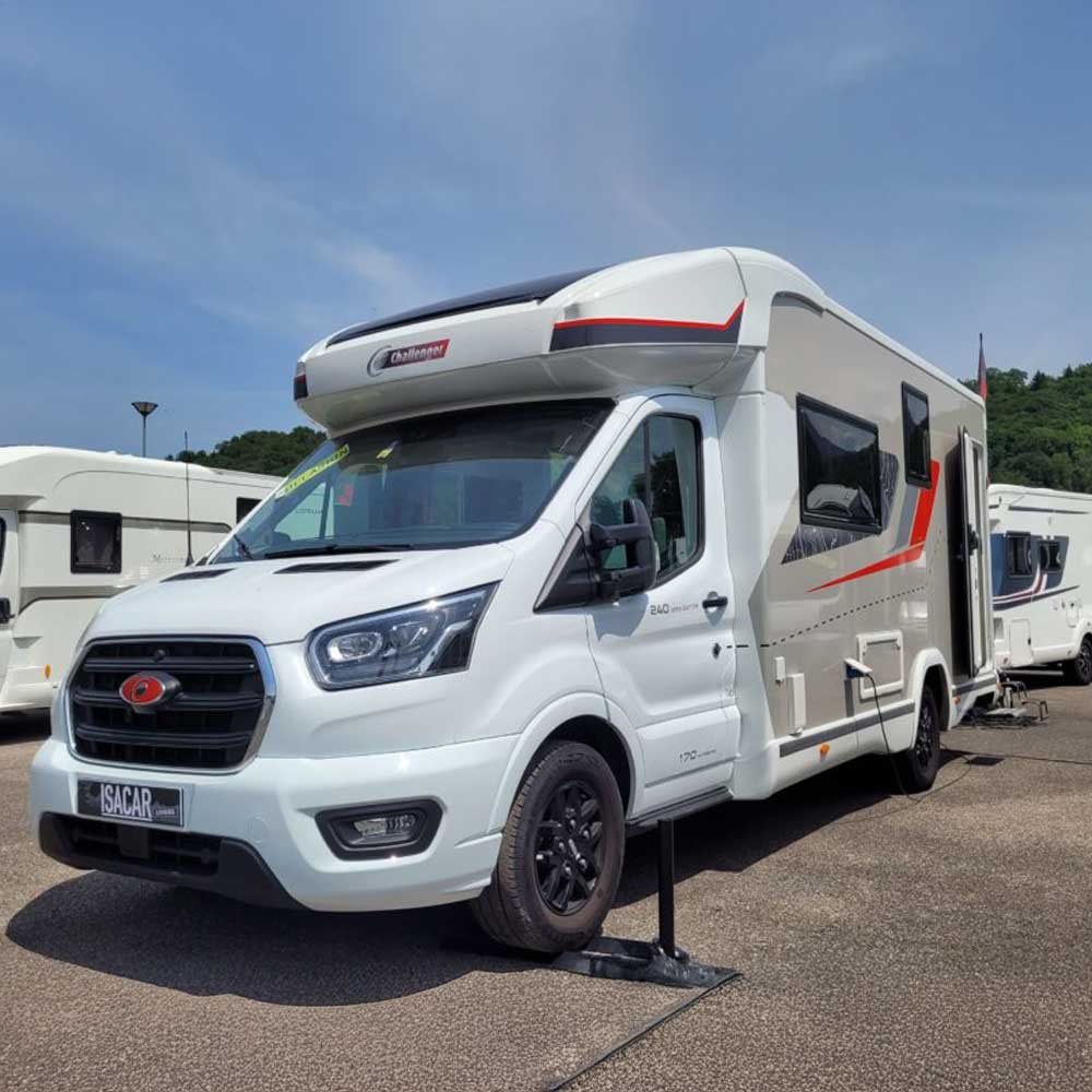Camping-car Challenger stationné sur un parking sous un ciel bleu.