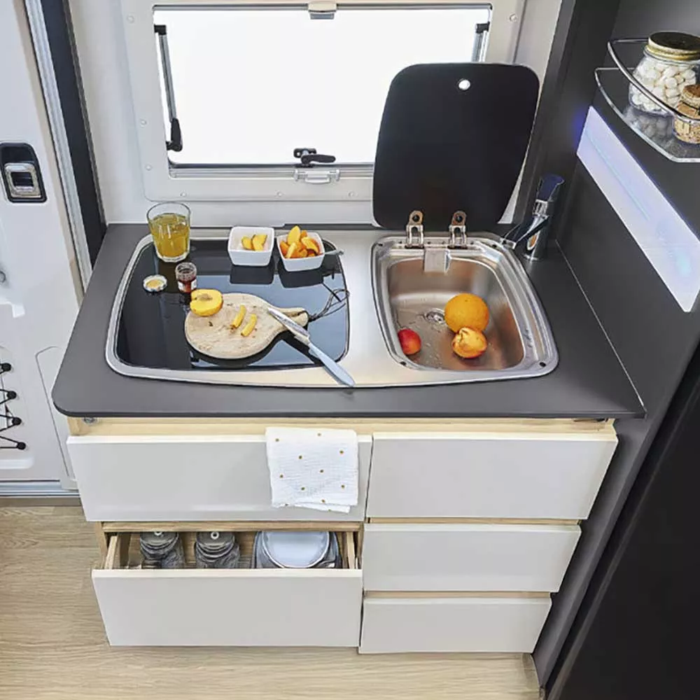 Cuisine compacte de camping-car avec évier, planche à découper et fruits