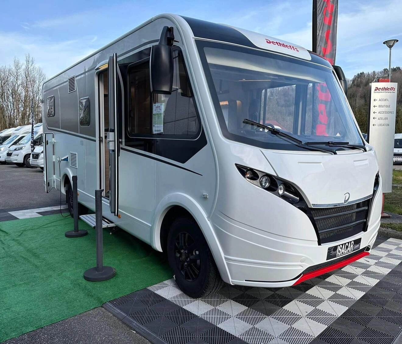Camping-car Dethleffs blanc exposé sur un parking avec d'autres véhicules similaires.