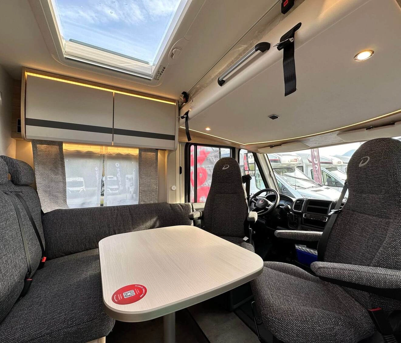 Intérieur d'un camping-car avec table, sièges et puits de lumière.