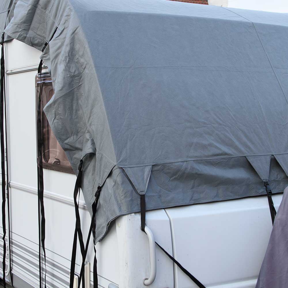 Bâche de protection grise couvrant le toit d'une caravane stationnée.