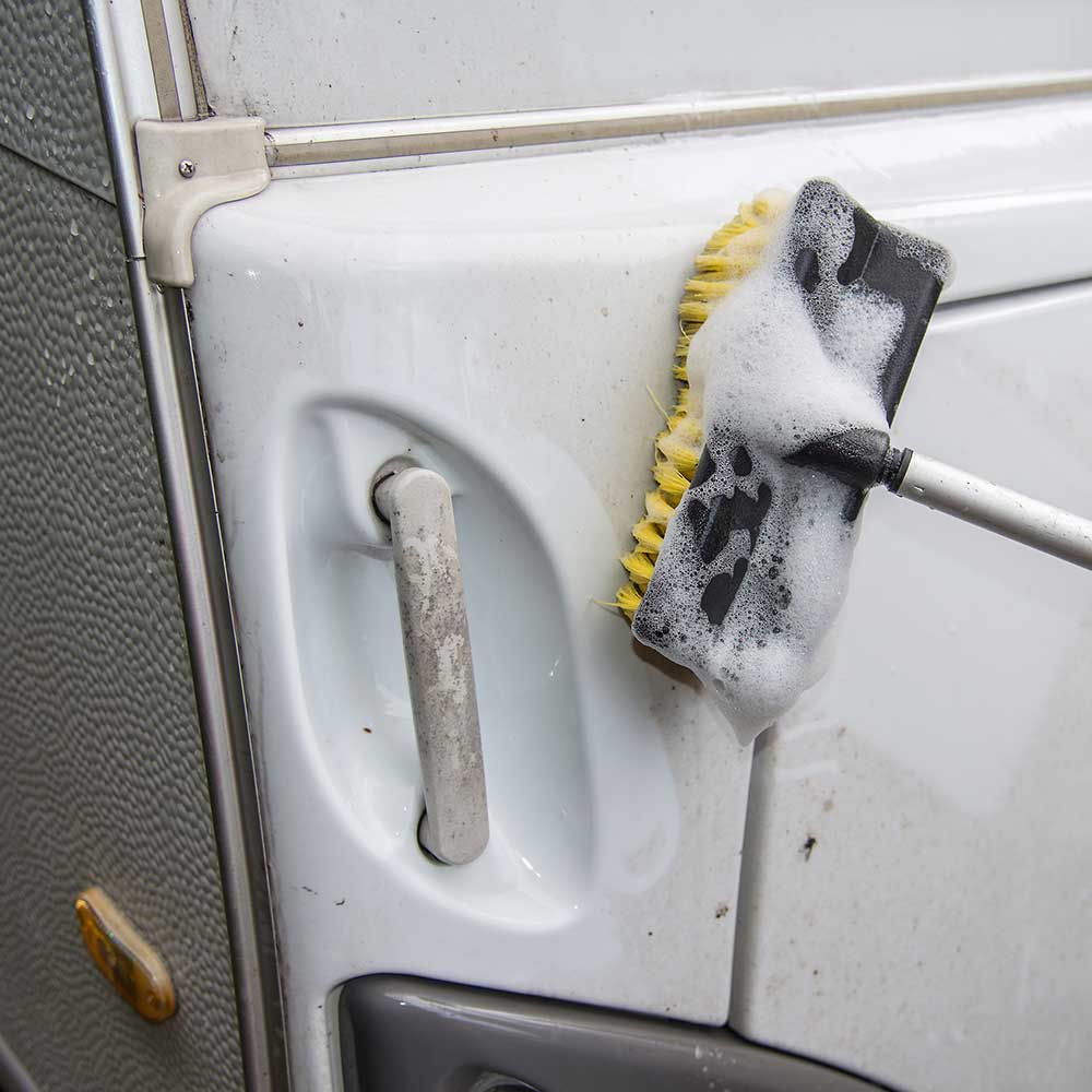 Nettoyage d'une caravane avec une brosse savonneuse