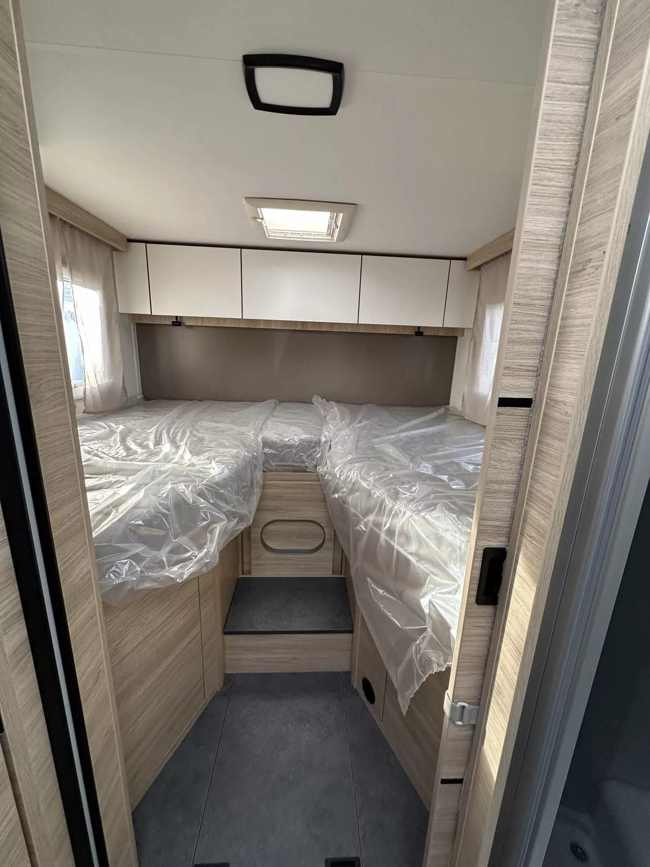 Intérieur d'une caravane avec lits jumeaux et rangements en bois clair.