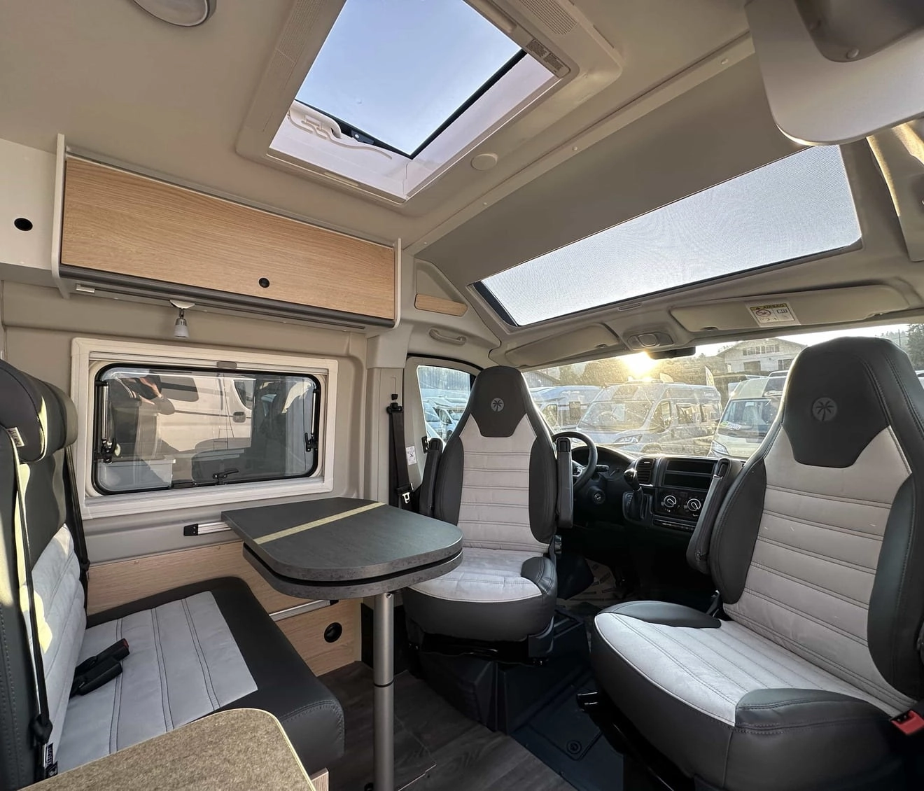 Intérieur d'un camping-car moderne avec sièges et table, éclairage naturel.