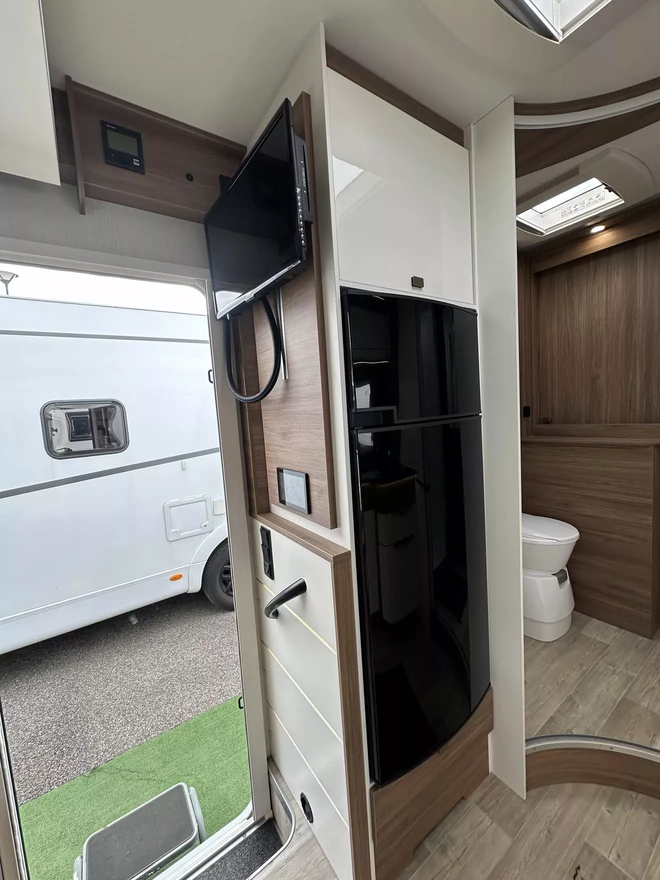 Intérieur d'un camping-car moderne avec télévision et salle de bain visible.