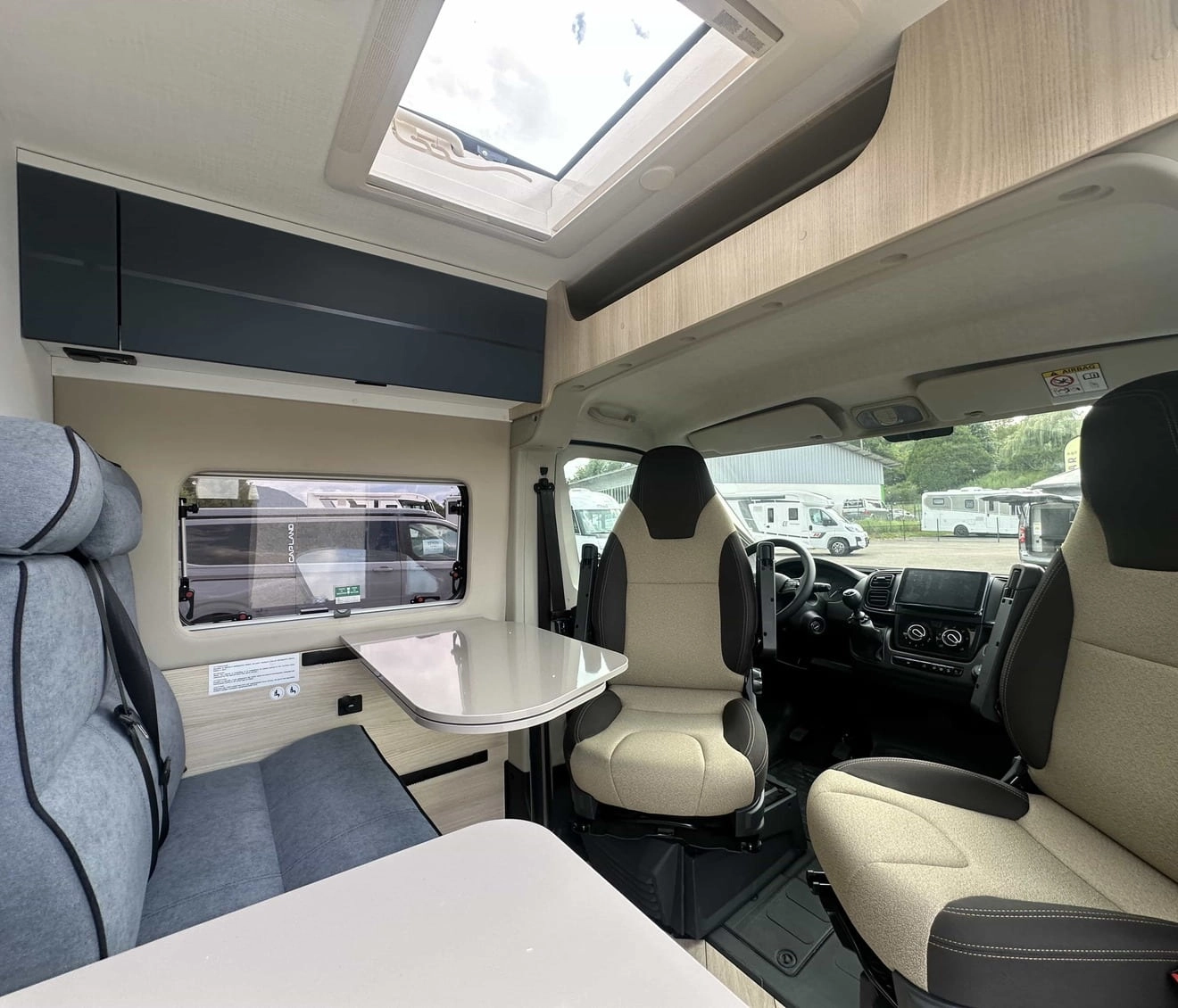 Intérieur d'un camping-car moderne avec sièges et table pliante.