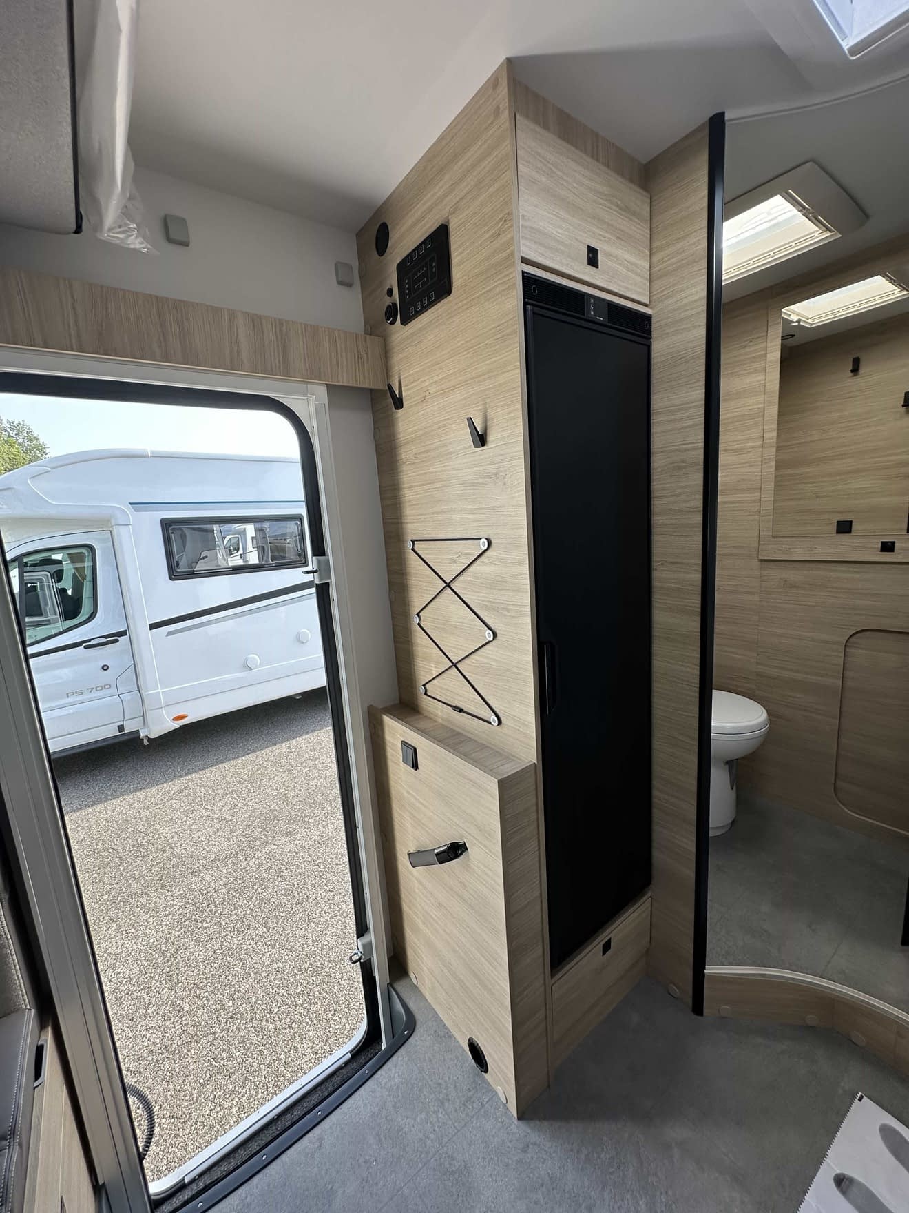Intérieur d'un camping-car moderne avec salle de bain et mobilier en bois clair.