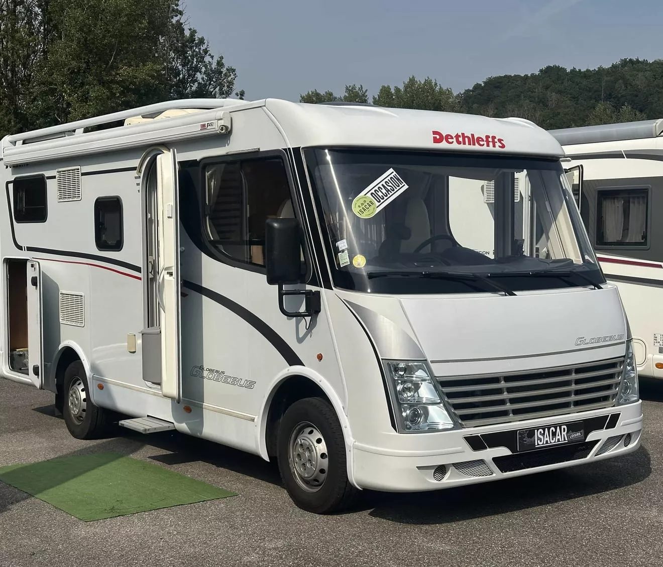Camping-car Dethleffs blanc stationné sur un parking, porte ouverte