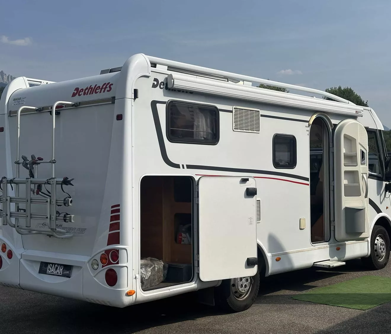Camping-car Dethleffs stationné avec porte ouverte et porte-vélos à l'arrière.