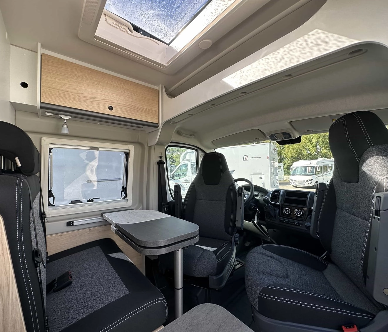Intérieur d'un camping-car moderne avec sièges et table pliante.