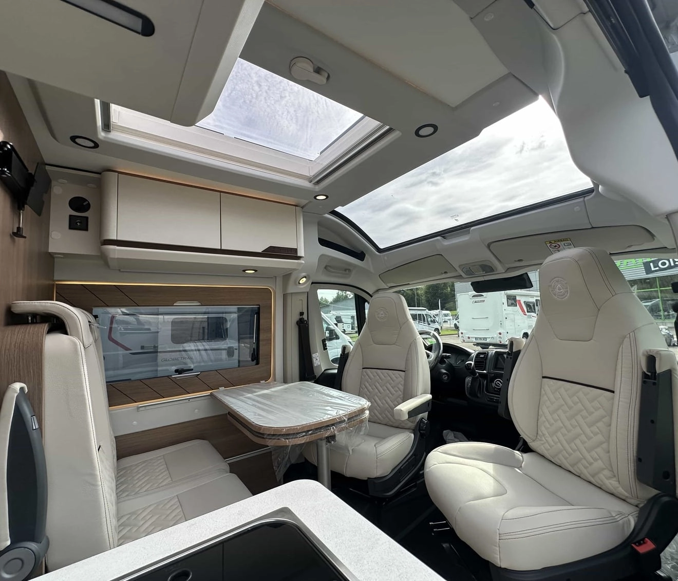 Intérieur d'un camping-car moderne avec sièges en cuir et toit panoramique.