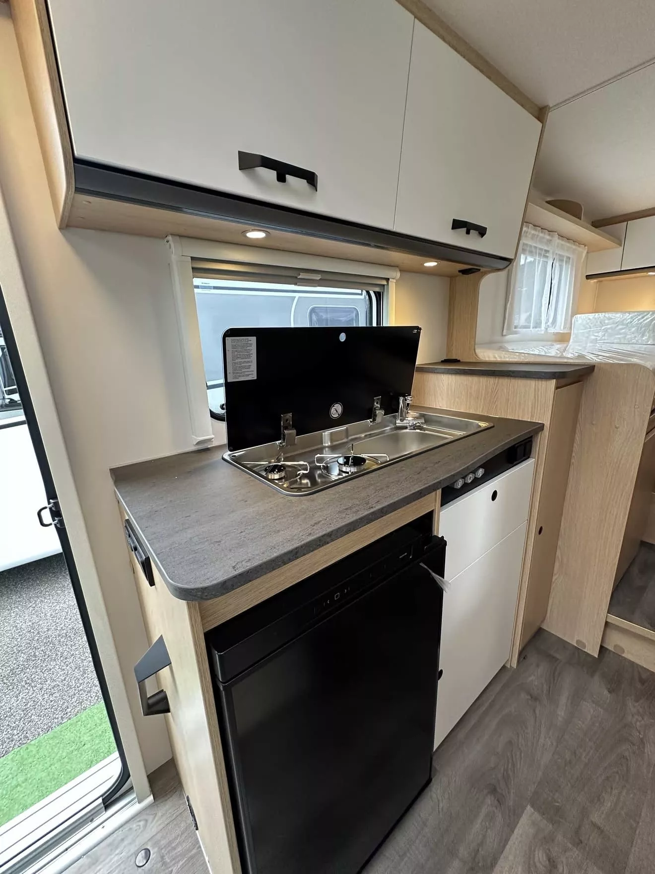 Cuisine compacte de camping-car avec évier, réfrigérateur et rangements.