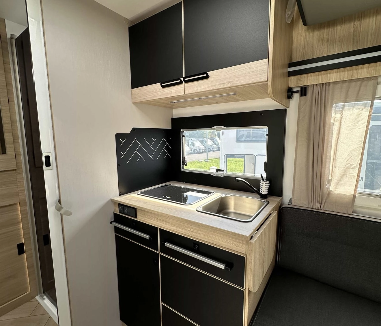 Intérieur moderne de cuisine de camping-car avec évier et rangements noirs et bois.