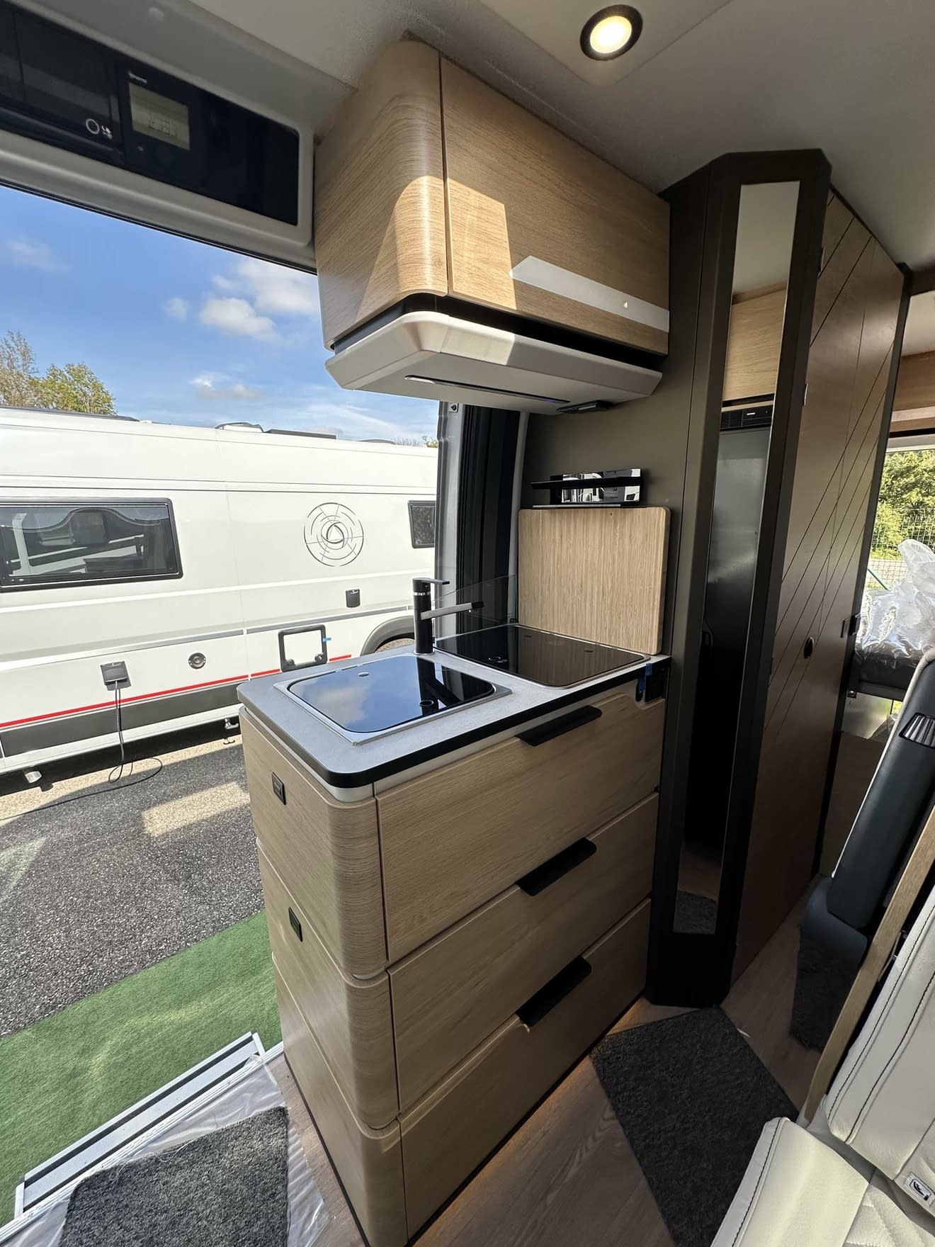 Intérieur moderne d'un camping-car avec cuisine équipée et rangements en bois clair.