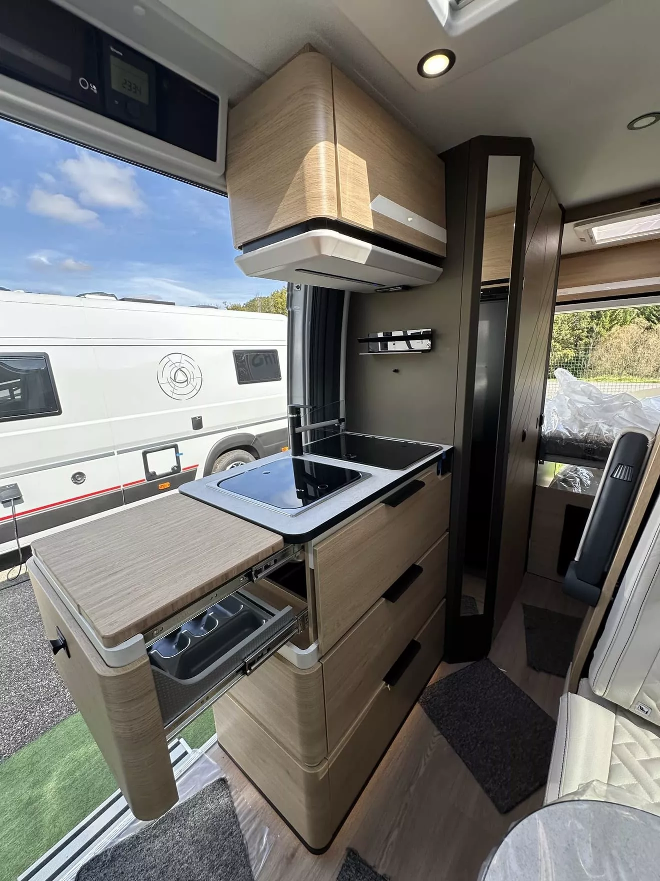 Intérieur moderne d'un camping-car avec cuisine équipée et rangements en bois clair.