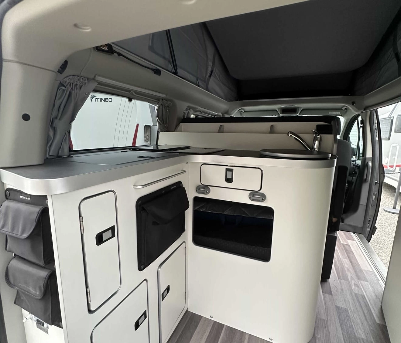 Intérieur d'un van aménagé avec cuisine compacte et rangements intégrés.