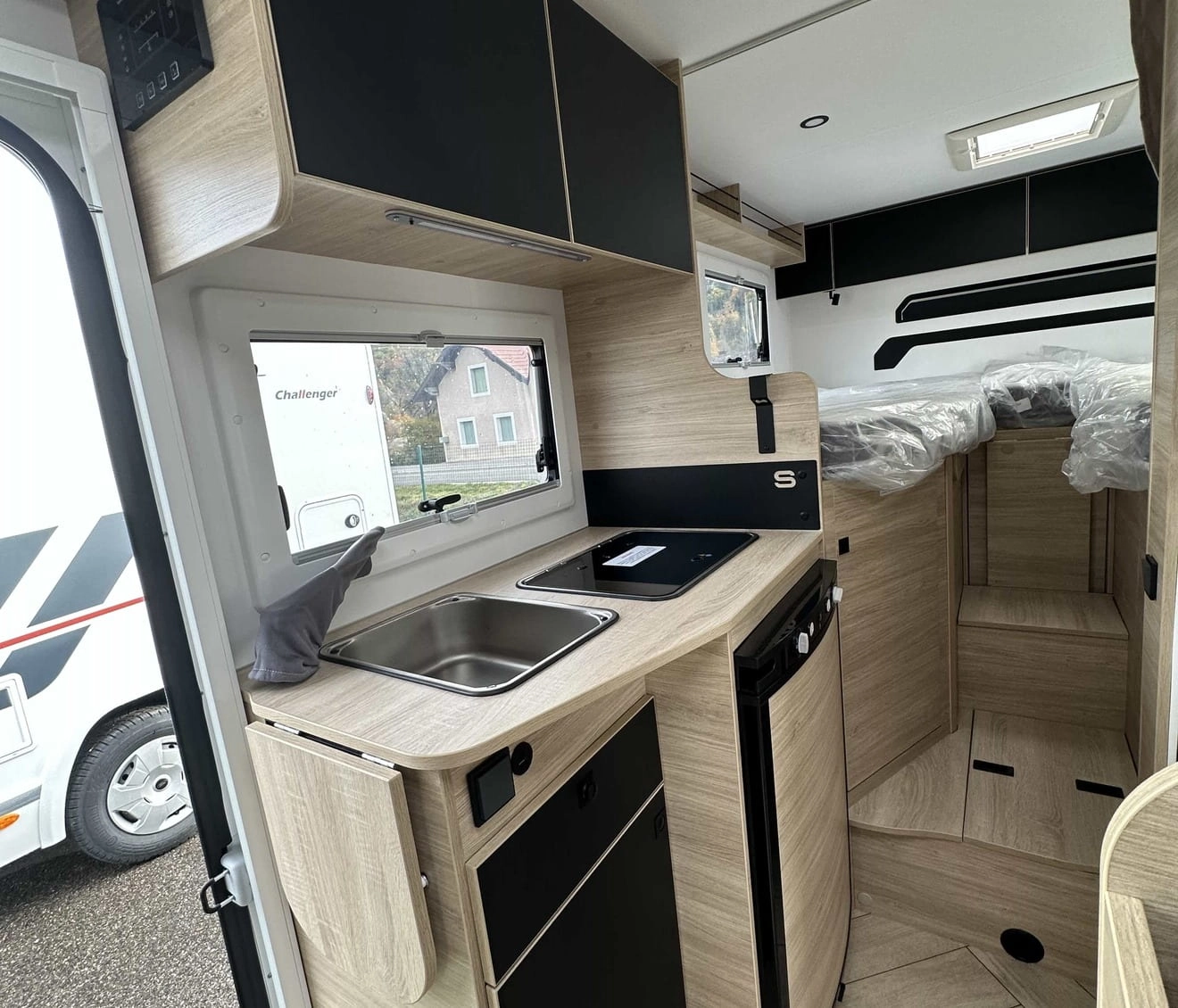 Intérieur moderne d'un camping-car avec cuisine équipée et rangements en bois clair.