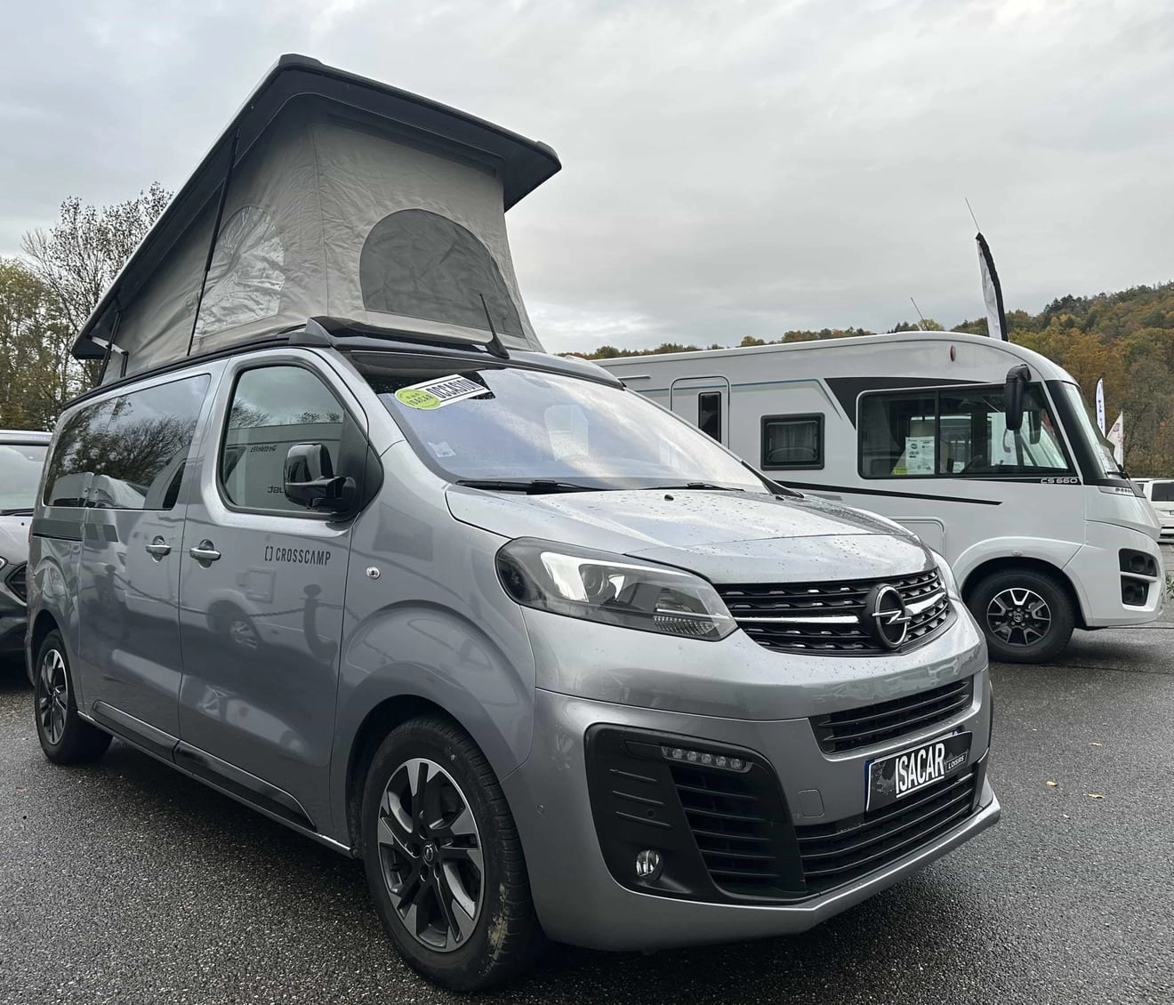 Van Opel Crosscamp avec toit relevable sur un parking de camping-cars.