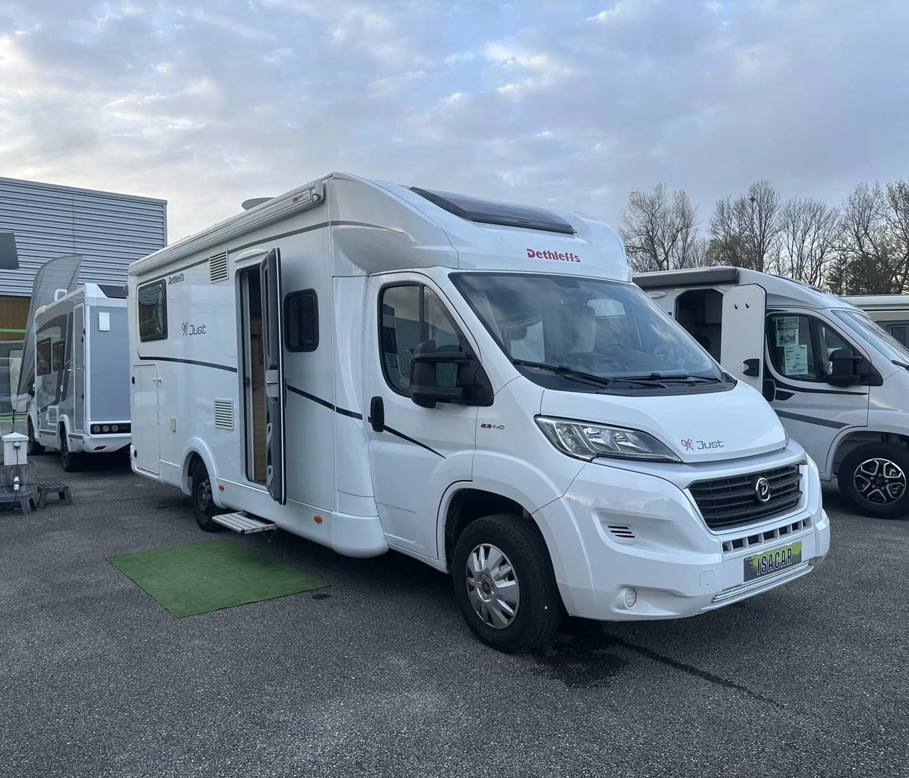 Camping-car Dethleffs blanc stationné sur un parking, ciel nuageux en arrière-plan