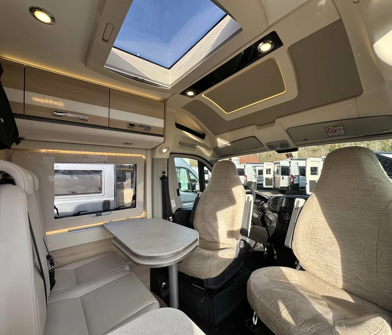 Intérieur d'un camping-car moderne avec sièges et table, vue sur le toit ouvrant.