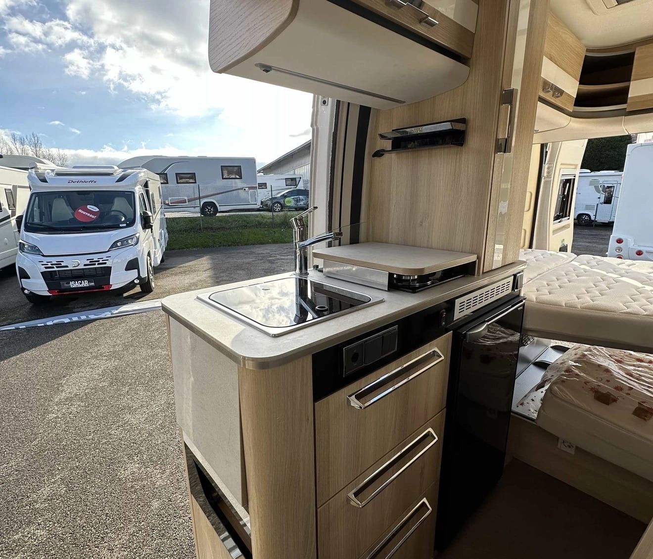 Intérieur d'un camping-car moderne avec cuisine équipée et espace de couchage.
