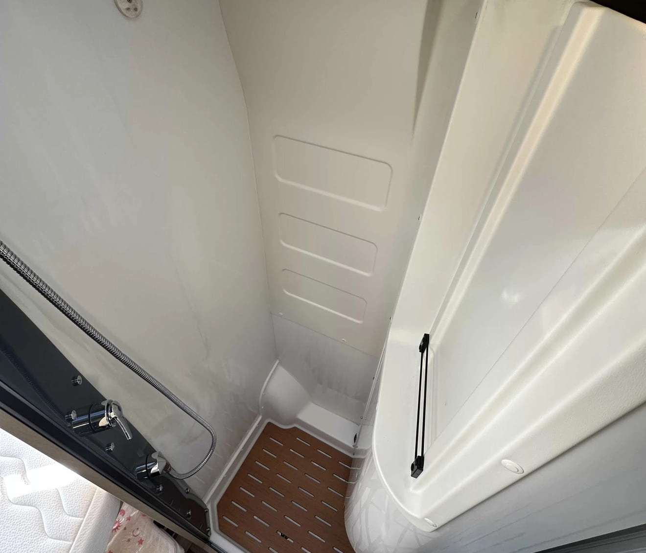 Douche compacte avec sol en bois dans un camping-car moderne.