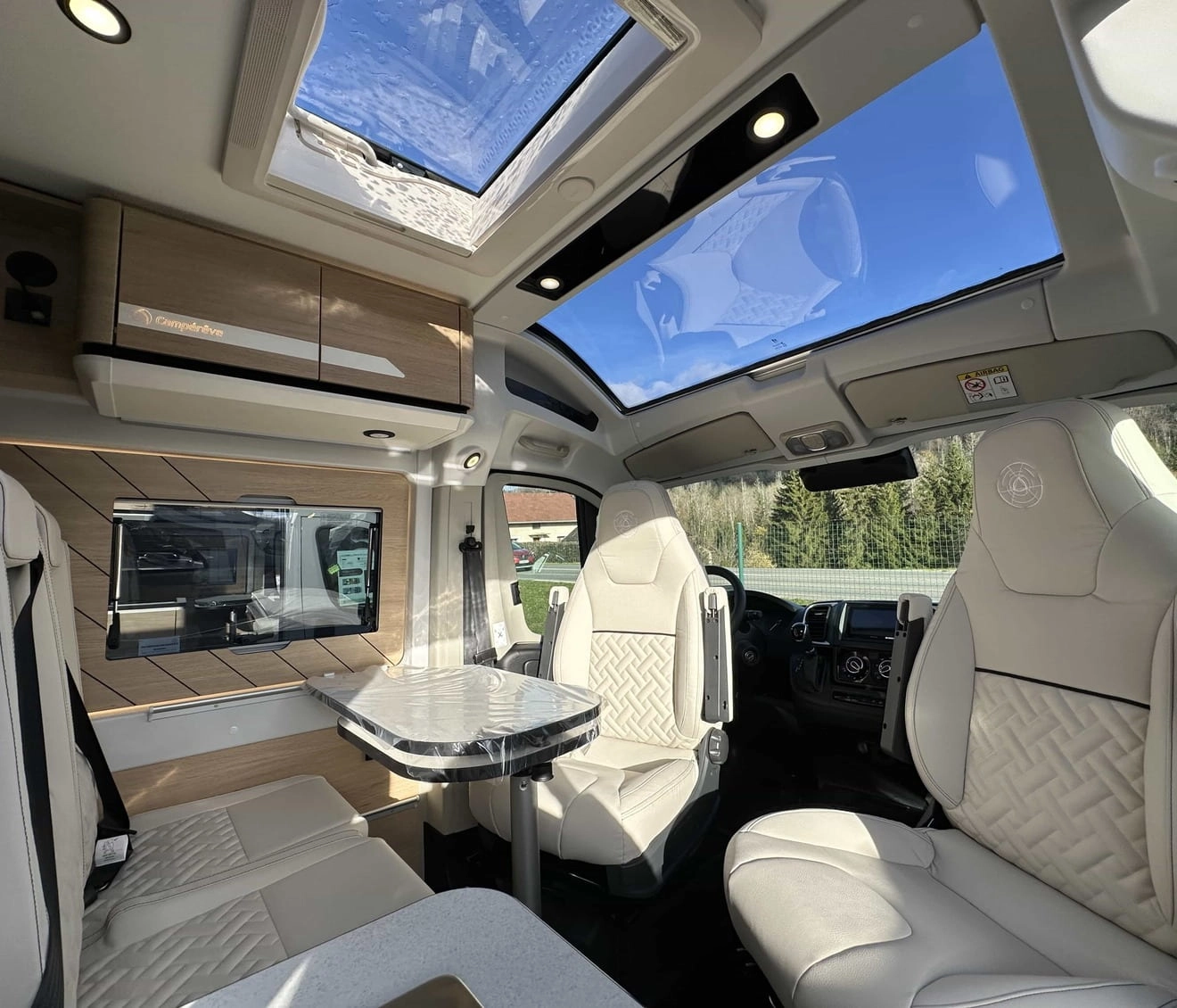 Intérieur d'un camping-car moderne avec sièges en cuir et toit panoramique.
