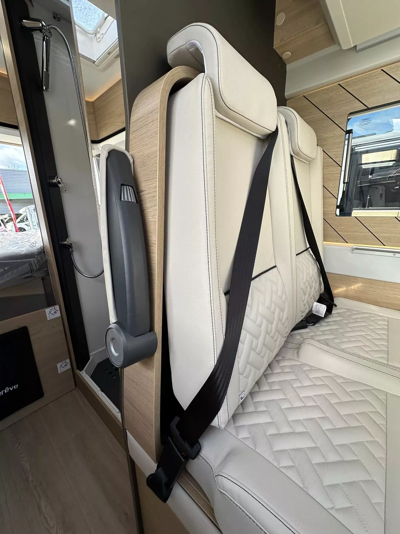 Siège de camping-car avec ceinture de sécurité et revêtement en cuir beige.