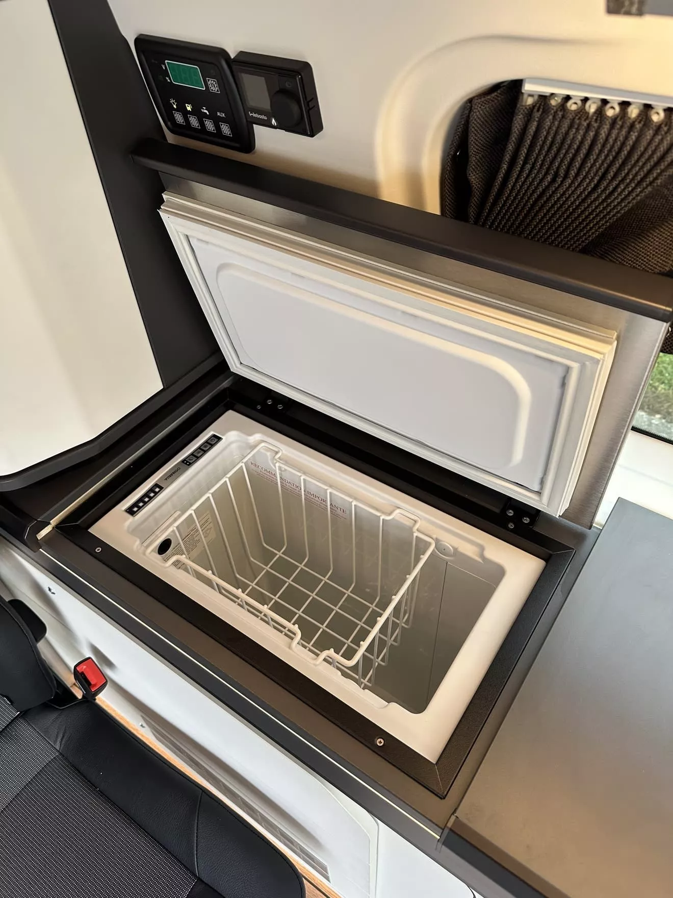 Réfrigérateur intégré dans un véhicule aménagé avec panneau de contrôle numérique.