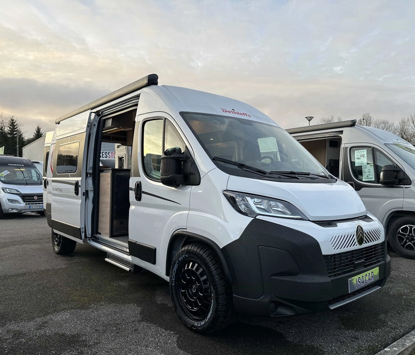 Camping-car blanc Dethleffs avec porte ouverte sur un parking