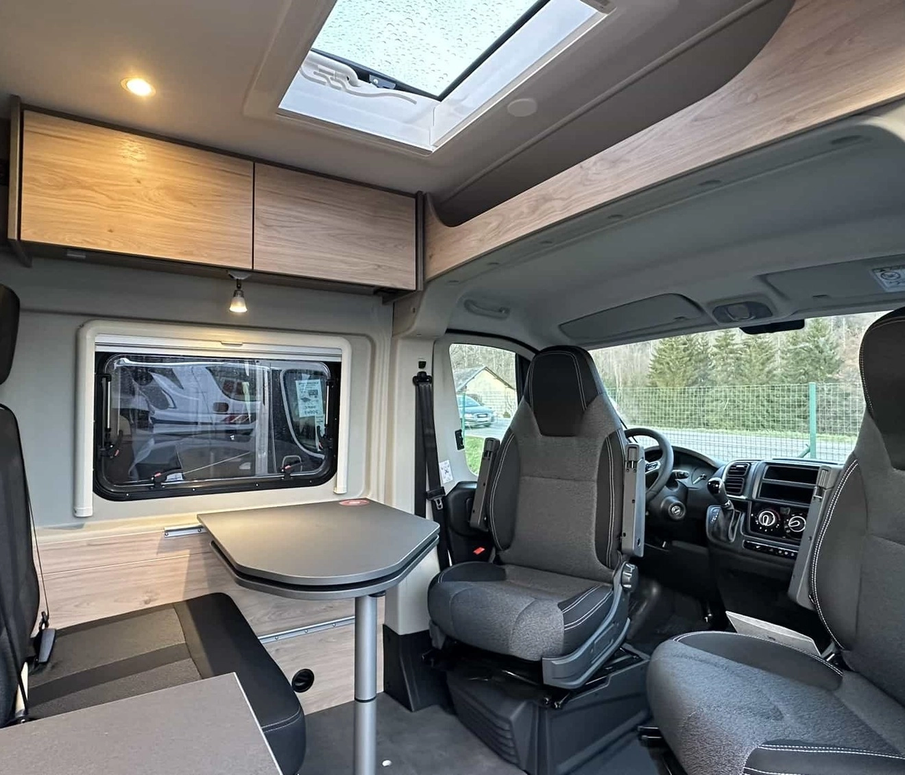 Intérieur d'un camping-car moderne avec sièges et table pliante.
