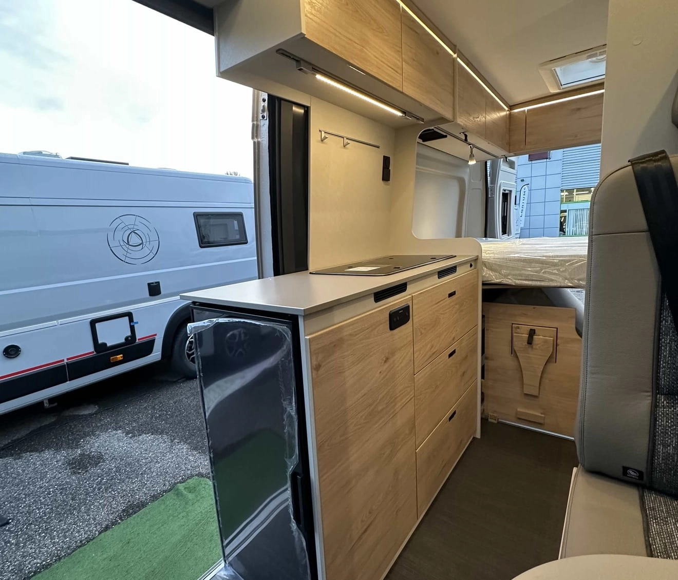 Intérieur moderne d'un camping-car avec cuisine équipée et rangements en bois clair.
