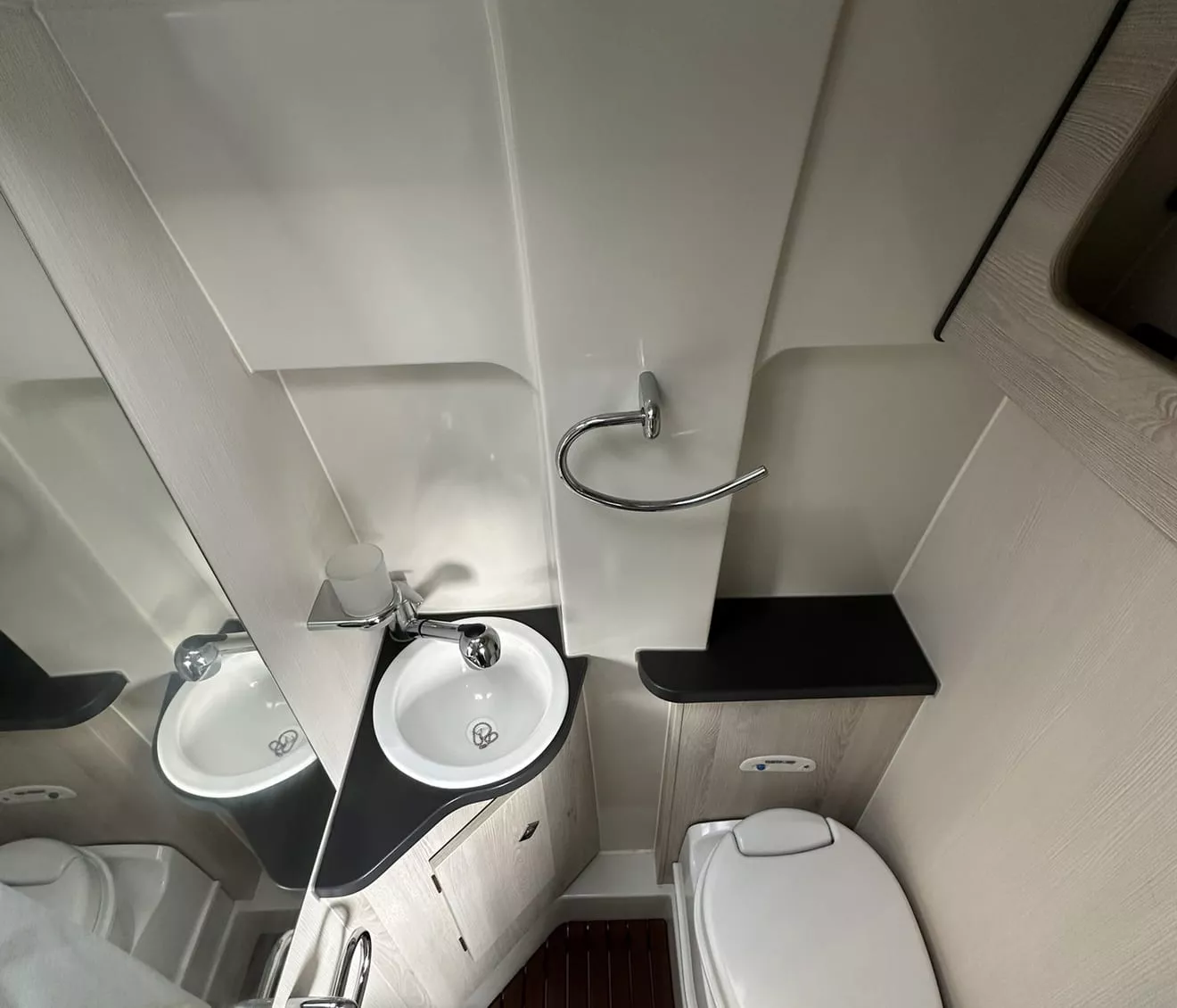 Salle de bain compacte avec lavabo, toilettes et douche dans un espace restreint.
