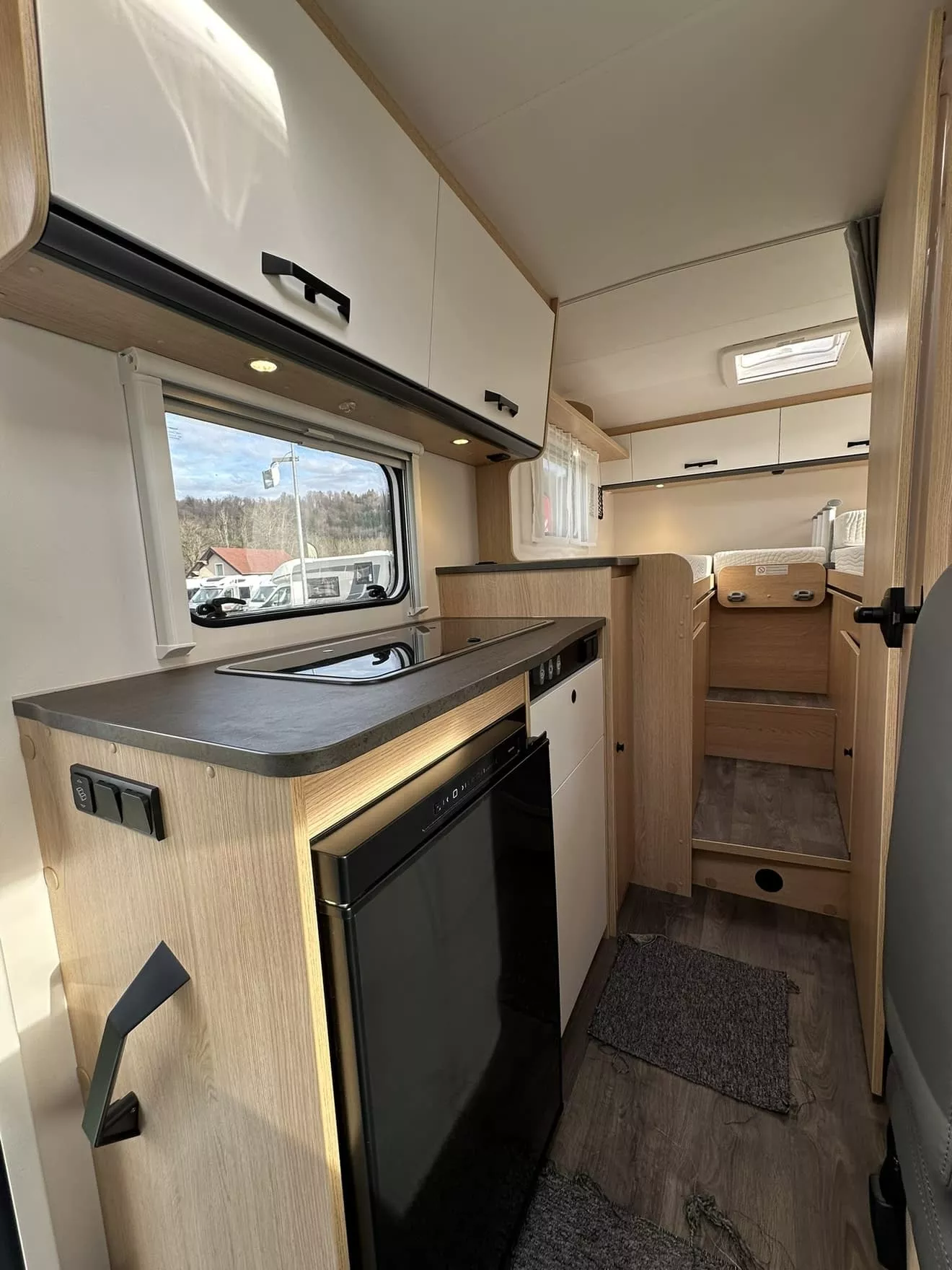 Intérieur moderne d'un camping-car avec cuisine équipée et espace couchage.