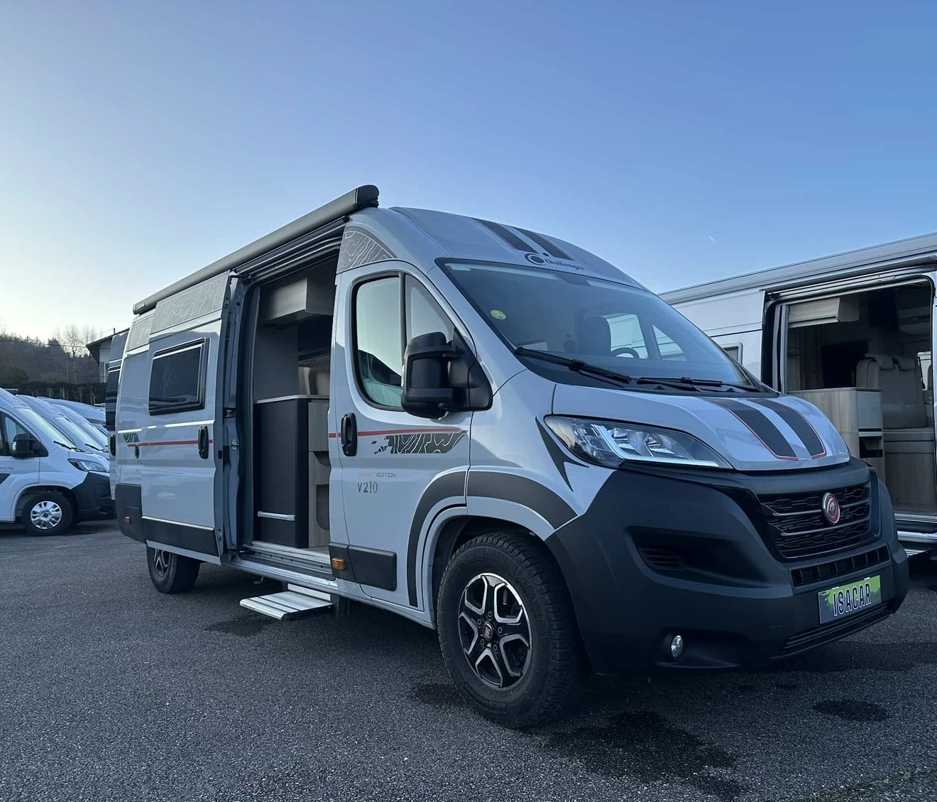 Camping-car gris stationné sur un parking, porte latérale ouverte
