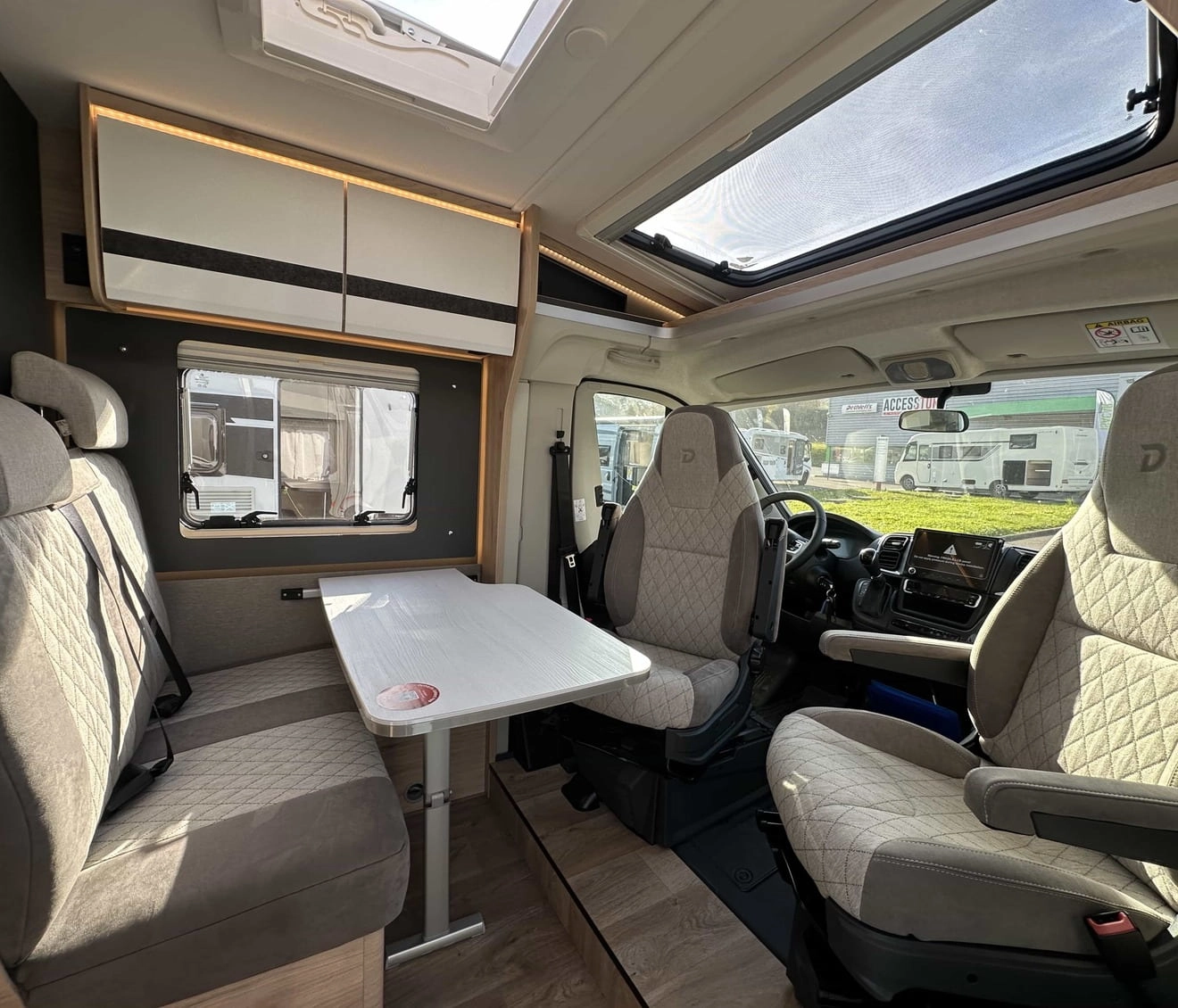 Intérieur d'un camping-car moderne avec sièges et table, éclairage naturel.