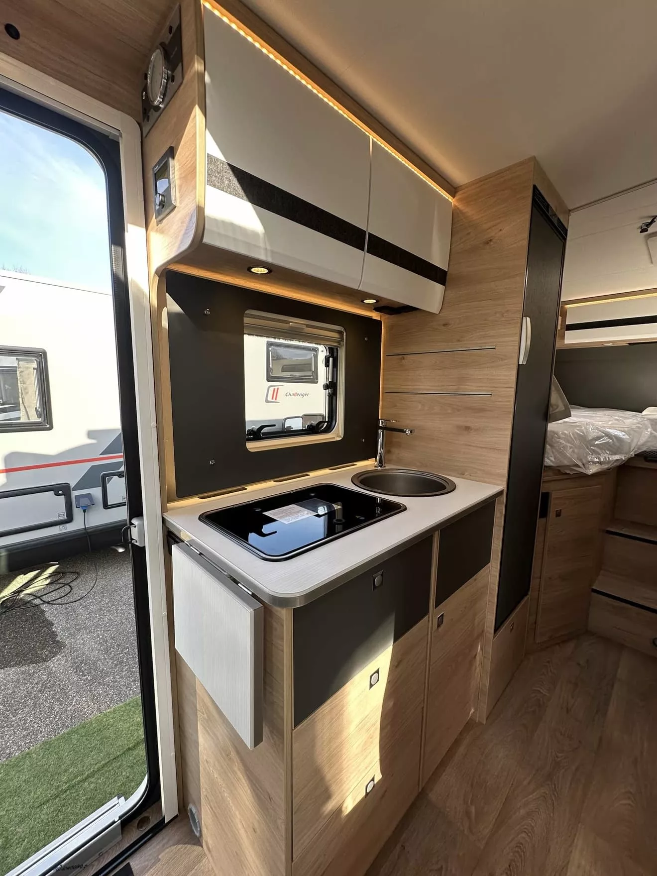 Intérieur d'une caravane avec kitchenette moderne et rangements en bois clair.