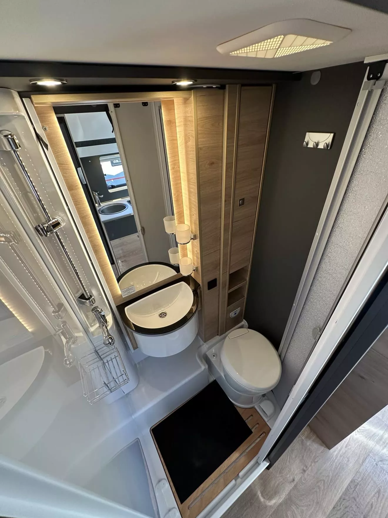 Salle de bain compacte avec lavabo, douche et toilettes dans un camping-car moderne.