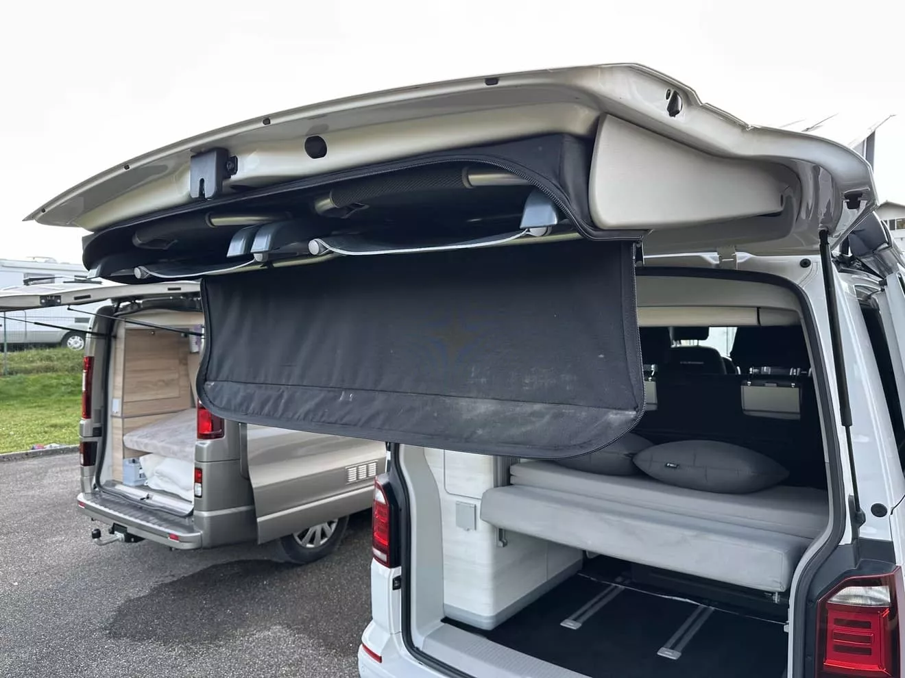 Vans aménagés avec lits rabattables et hayons ouverts sur un parking.