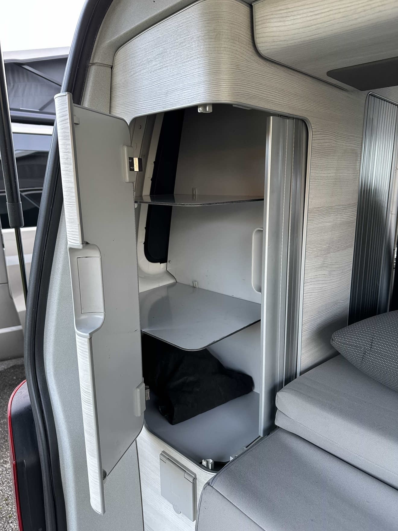 Rangement intérieur d'un van aménagé avec étagères et porte ouverte.